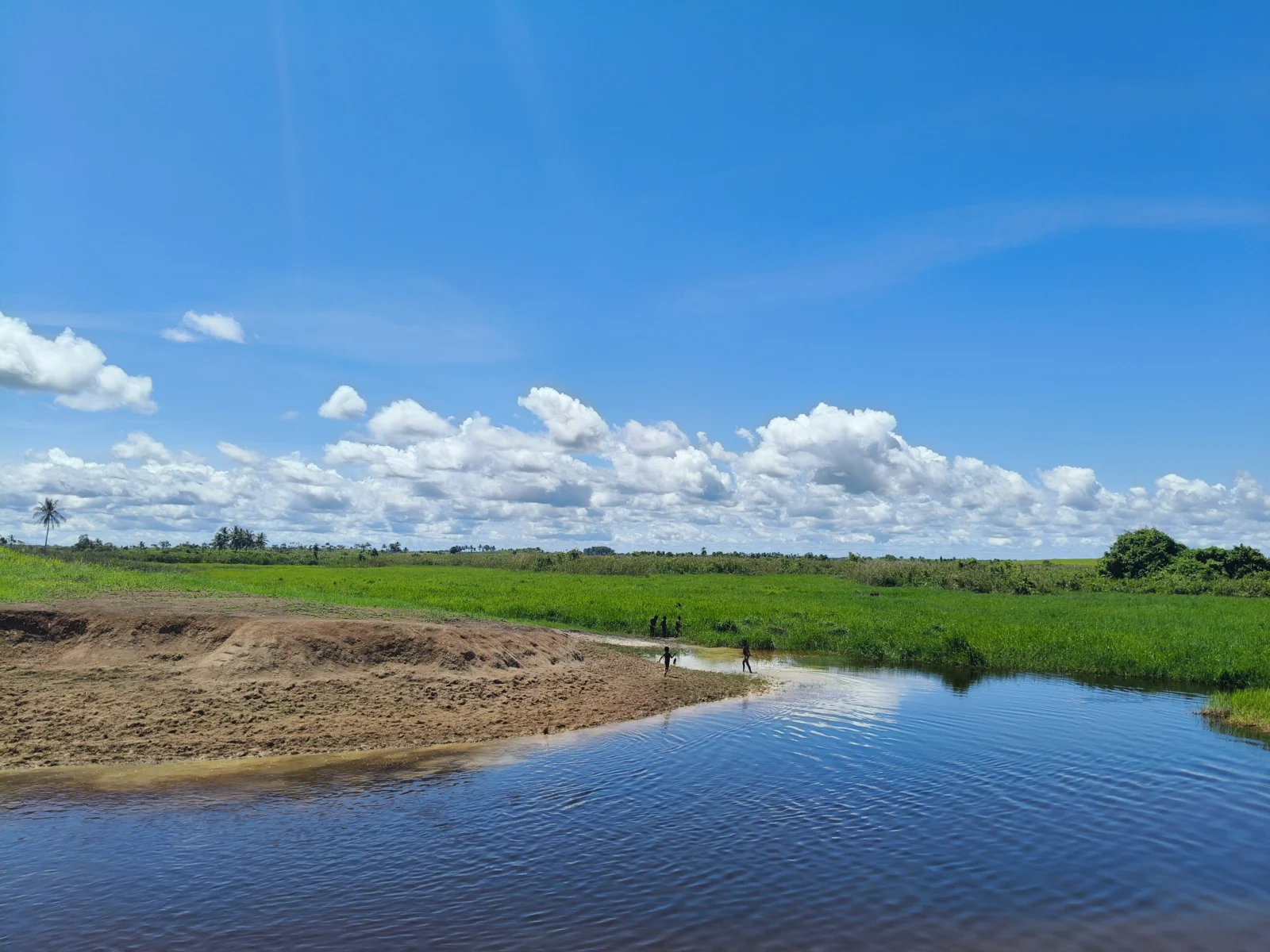 A calm river curves through the open green landscape on the way to Kotale, highlighting the remote terrain reached during the