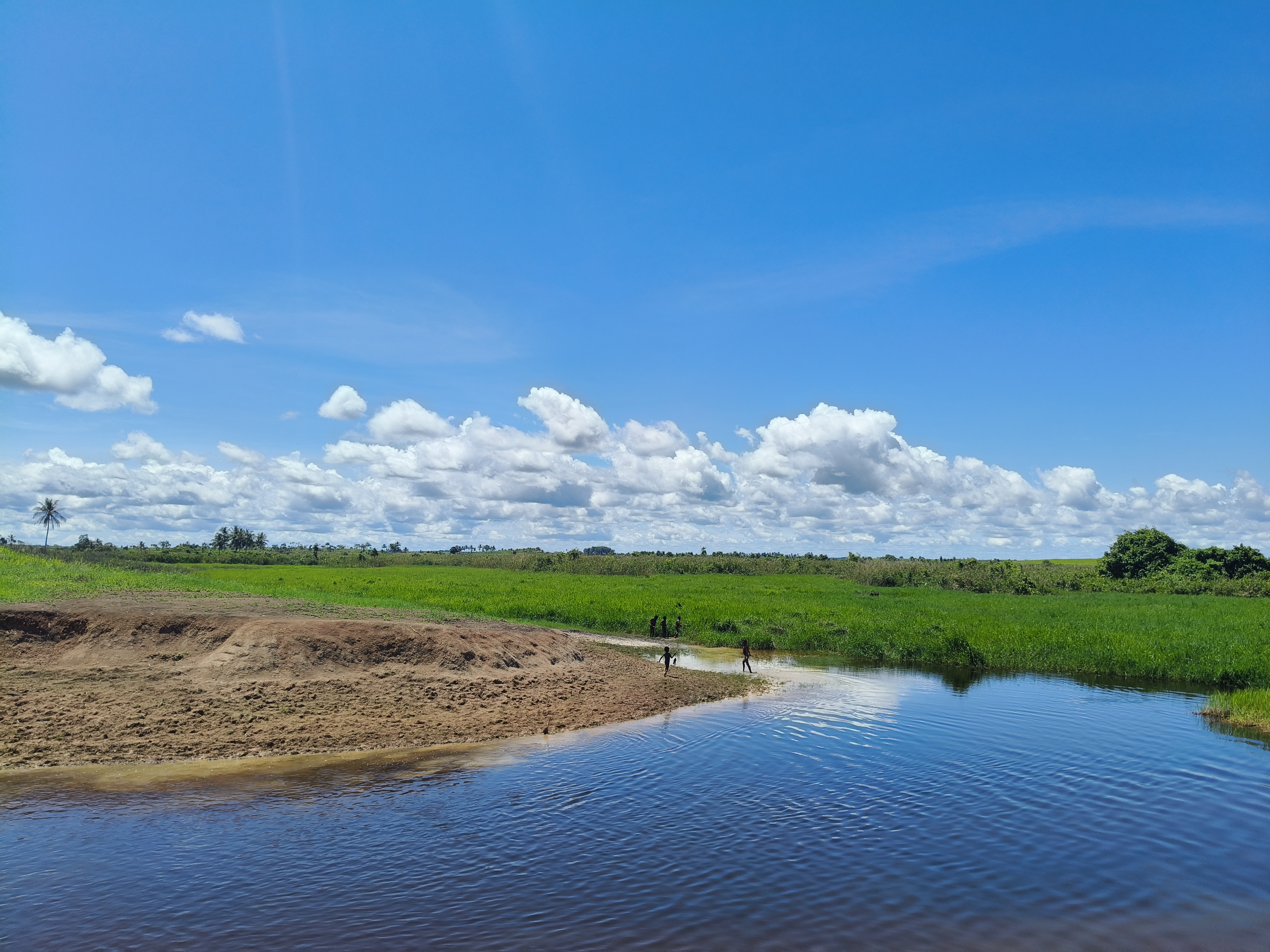 A calm river curves through the open green landscape on the way to Kotale, highlighting the remote terrain reached during the